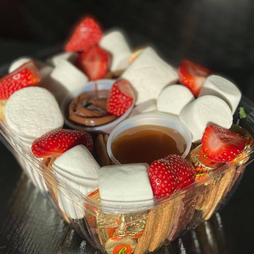 A dessert platter featuring strawberries, marshmallows, chocolate dip, and graham crackers.