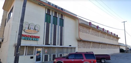 Exterior of Stone Sisters Pizza Bar, featuring a retro-style building with a pizza sign and a parked red vehicle.