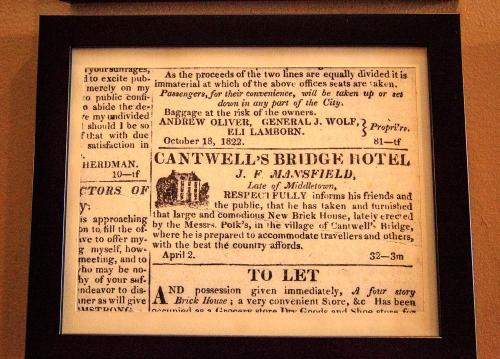 Framed vintage newspaper advertisement for Cantwell's Bridge Hotel, detailing services and property for rent.