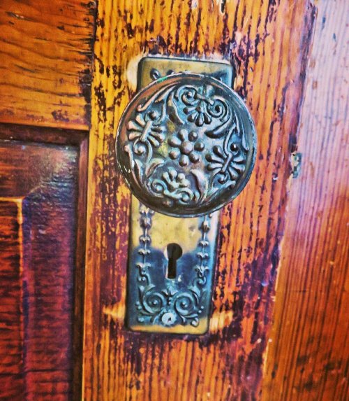 Close-up of an ornate vintage door lock with intricate floral designs on a wooden door.