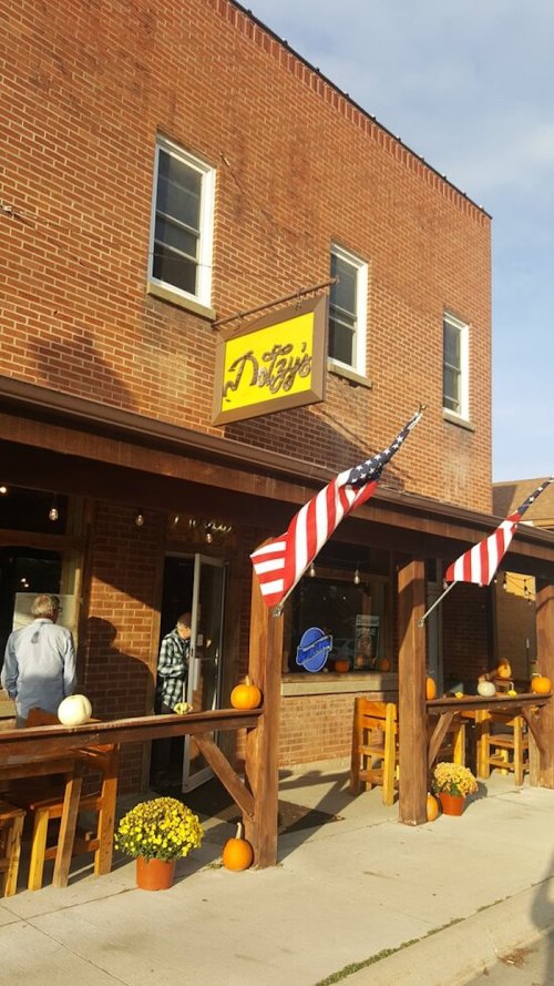 A brick building with a yellow sign reading "Duggy's," featuring American flags and pumpkins outside.