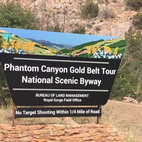 Sign for Phantom Canyon Gold Belt Tour National Scenic Byway, with a warning against target shooting within 1/4 mile.
