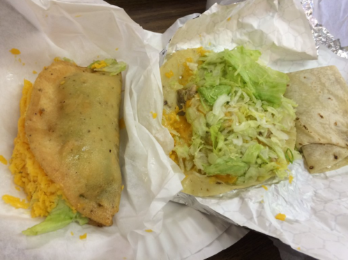 A plate with a stuffed tortilla, lettuce, and rice, alongside a folded tortilla filled with meat and topped with lettuce.
