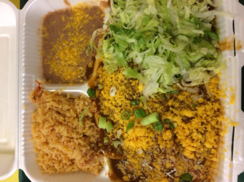 A takeout container with rice, refried beans, shredded lettuce, and a dish topped with cheese and green onions.