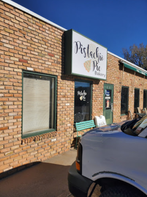 Exterior of Pistachio Pie Bakery, featuring a brick facade and a sign with the bakery's name. A vehicle is parked nearby.