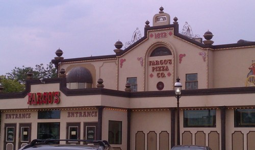 Exterior of Fargo's Pizza Co. featuring a decorative facade with lights and signage, under a cloudy sky.
