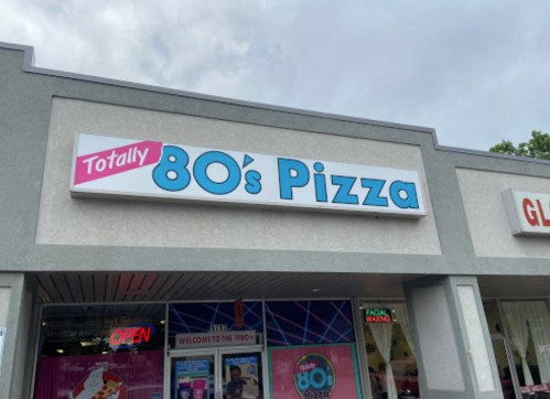 Sign for "Totally 80's Pizza" on a storefront, featuring bright colors and a retro design.