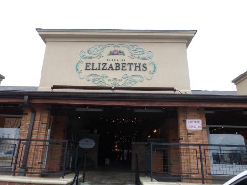 Sign for "Pizza by Elizabeths" on a building with a decorative design and outdoor seating area.