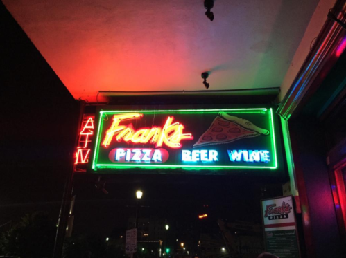 Neon sign for Frank's Pizza, Beer, and Wine, illuminated at night with an ATM sign above.