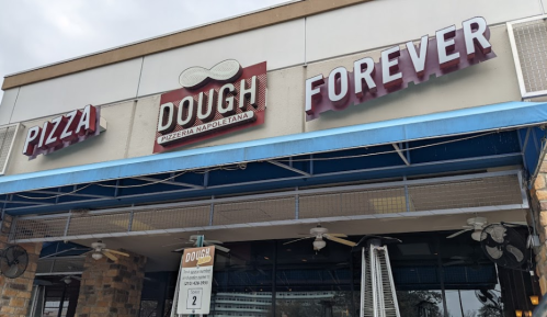 Sign for "Dough Forever" pizzeria, featuring the words "Pizza" and "Forever" in bold letters on a storefront.