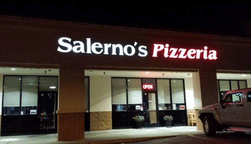Exterior of Salerno's Pizzeria at night, featuring a lit "OPEN" sign and a parked vehicle in front.