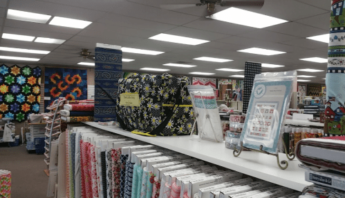 A fabric store interior showcasing colorful fabrics, bags, and quilting supplies on display shelves.