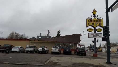 Exterior of Ranch House Cafe with a sign, cloudy sky, and parking lot visible.