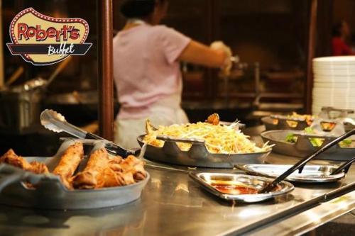 A buffet display featuring various dishes, including spring rolls and salad, with a staff member in the background.