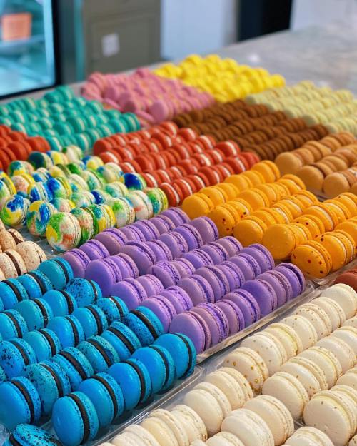 A colorful display of macarons in various flavors and vibrant hues arranged neatly on a table.