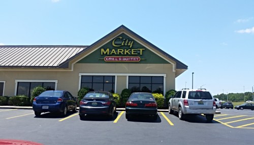 Exterior of City Market Grill & Buffet with parked cars in front and a clear blue sky.