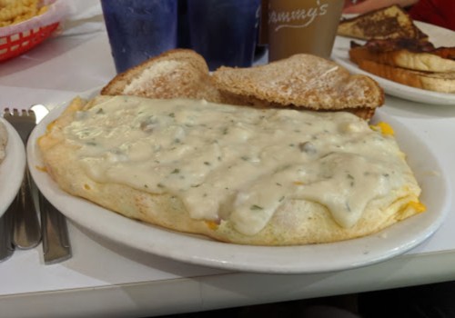 A plate with a large omelet covered in creamy gravy, served with two slices of toasted bread.