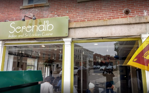 Exterior of Serendib restaurant, featuring a sign for Indian and Sri Lankan cuisine, with people dining inside.