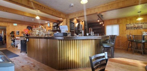 Cozy wooden café interior with a rustic bar, shelves, and seating, featuring warm lighting and a welcoming atmosphere.