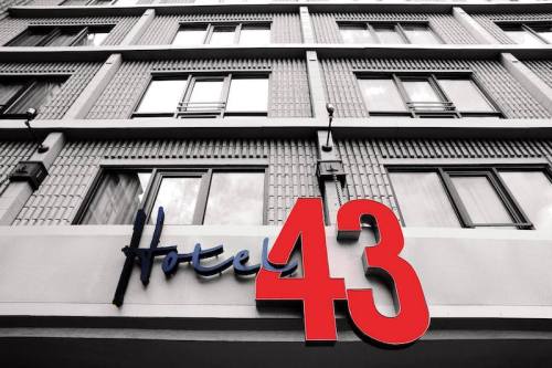 Sign for Hotel 43 in bold red letters, displayed below a modern building with multiple windows.