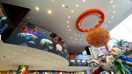 Colorful interior of a modern space featuring vibrant decor, large hanging art, and illuminated displays.