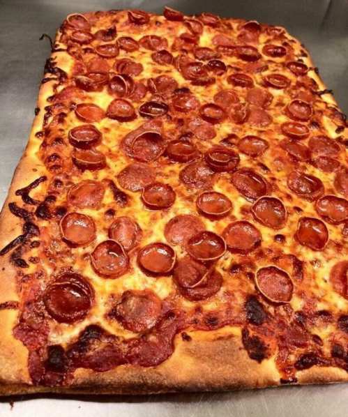 A rectangular pizza topped with melted cheese and numerous slices of pepperoni, with a golden-brown crust.