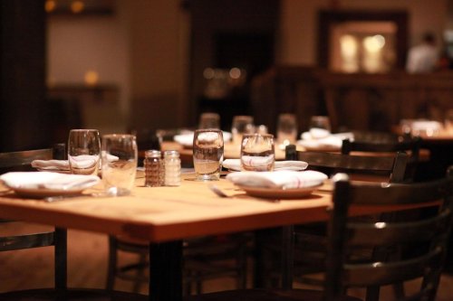 A dimly lit restaurant table set with glasses, napkins, and silverware, creating an inviting dining atmosphere.