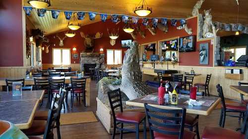 Cozy restaurant interior with wooden decor, animal mounts, and tables set for dining.