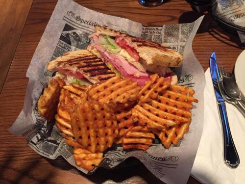 A toasted sandwich with turkey, lettuce, tomato, and onion, served with a side of crispy waffle fries.