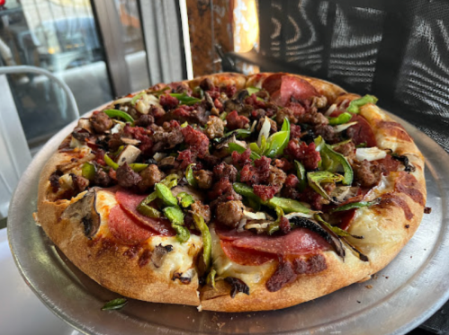 A delicious pizza topped with pepperoni, sausage, green peppers, and onions on a golden crust.