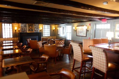 Cozy restaurant interior with wooden beams, leather chairs, and warm lighting, featuring tables and a fireplace.