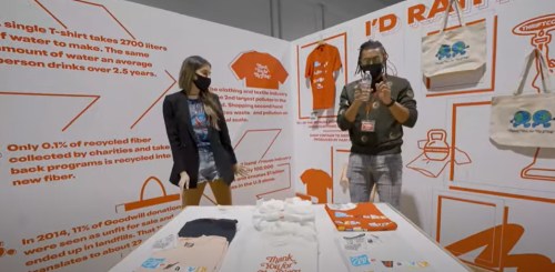 A man and woman discuss sustainable fashion at an exhibit, surrounded by informative displays and eco-friendly merchandise.