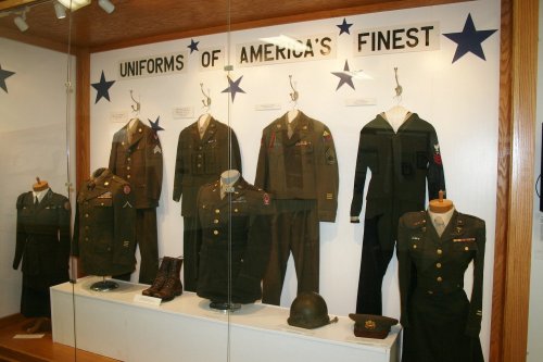 Display of military uniforms labeled "Uniforms of America's Finest," featuring various styles and accessories.