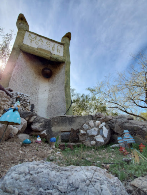 A whimsical stone tower labeled "Magic Tower" surrounded by colorful decorations and greenery under a blue sky.