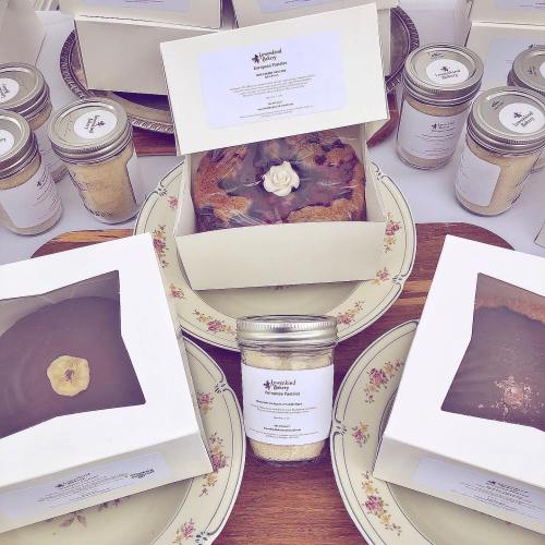 A display of baked goods in boxes and jars, featuring cakes and a jar of mix, all elegantly arranged on a tray.