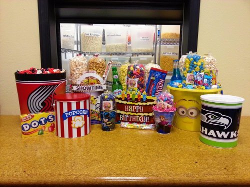 A colorful display of various snacks and candies in themed containers, including popcorn, soda, and birthday decorations.