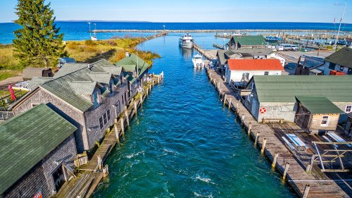 Aerial view of a marina with wooden docks, boats, and charming buildings along a blue waterway.