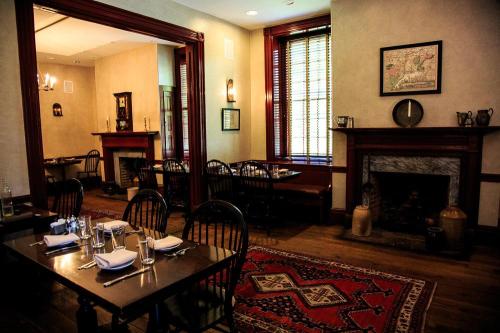 Cozy dining room with wooden tables, chairs, and a fireplace, featuring warm lighting and a decorative rug.