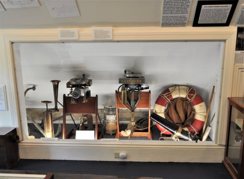 Display case featuring vintage maritime instruments, including a lifebuoy, compasses, and other nautical equipment.
