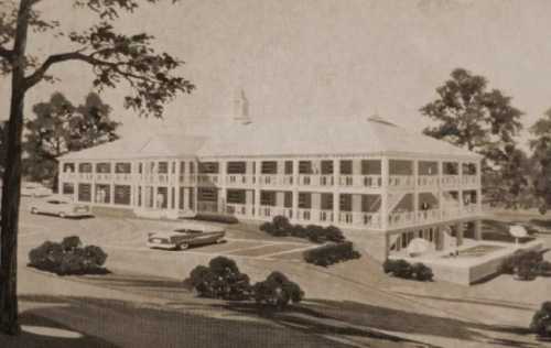 A vintage illustration of a large, two-story building with a wraparound porch, surrounded by trees and classic cars.