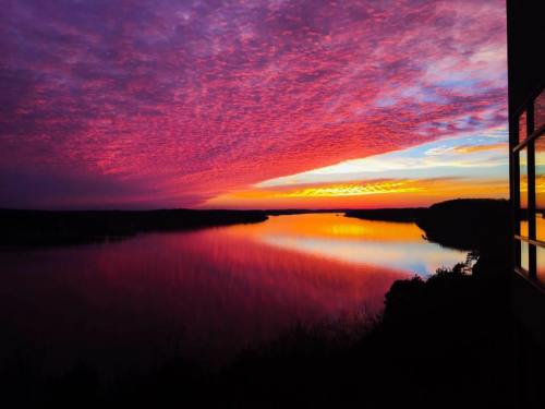 Vibrant sunset over a calm lake, with colorful clouds reflecting on the water's surface.