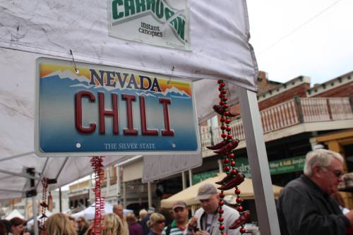 A sign reading "Nevada Chili" hangs at a market stall, with people browsing in the background.