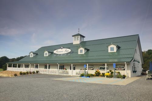 A large, white barn-style building with a green metal roof, featuring a sign for "Frances Inn" and landscaped surroundings.