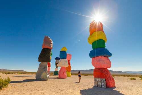 A person stands near colorful rock formations in the desert, with a bright sun shining above. "Spread Love" is visible.