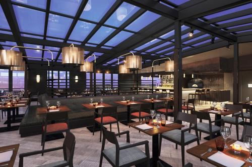 Modern restaurant interior with sleek furniture, ambient lighting, and a glass ceiling showcasing a twilight sky.