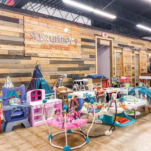 A colorful children's play area with toys, playsets, and a cozy wooden wall backdrop.