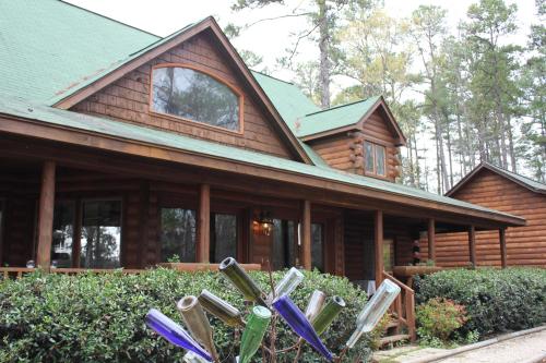 A log cabin with a green roof surrounded by trees, featuring a decorative arrangement of colorful bottles in the foreground.