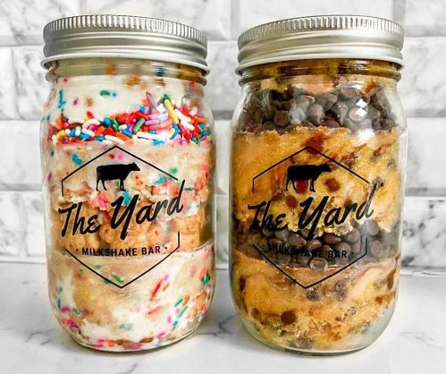 Two jars filled with colorful milkshake ingredients and cookie dough, labeled "The Yard Milkshake Bar."