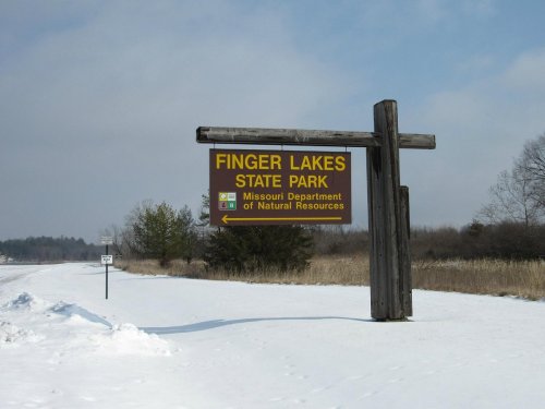 Sign for Finger Lakes State Park in Missouri, surrounded by snow and trees, indicating natural resources department.