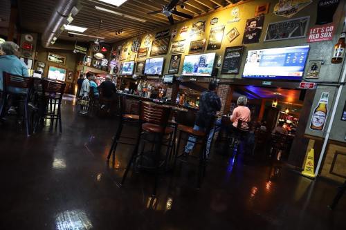 A lively bar interior with patrons, vintage decor, and multiple screens displaying sports events.